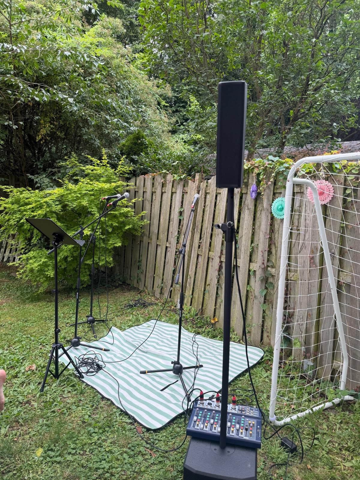 Open-Air-Setup von Four Pies Later im Garten: Mikrofonständer, Aktivbox und Mischpult am Beckenrand